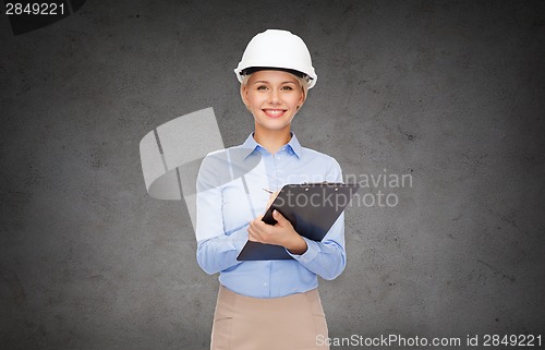 Image of smiling businesswoman in helmet with clipboard