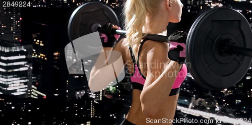 Image of sporty woman exercising with barbell from back