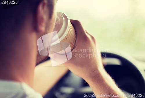 Image of man drinking coffee while driving the car