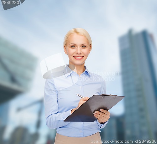 Image of smiling businesswoman with clipboard and pen