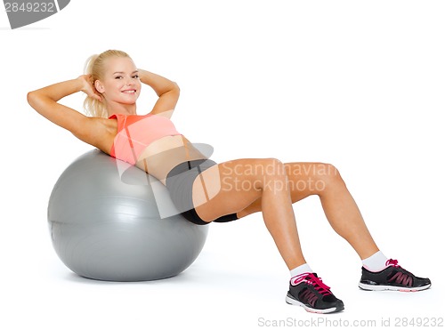 Image of smiling sporty woman exercising on fitness ball