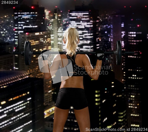 Image of sporty woman exercising with barbell from back