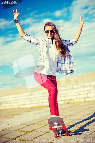 Image of smiling teenage girl riding skate outside