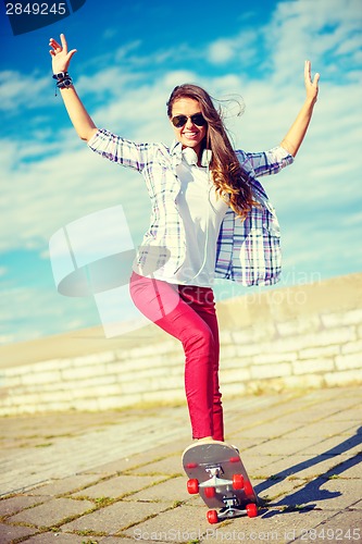 Image of smiling teenage girl riding skate outside