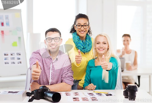 Image of smiling team with printed photos working in office