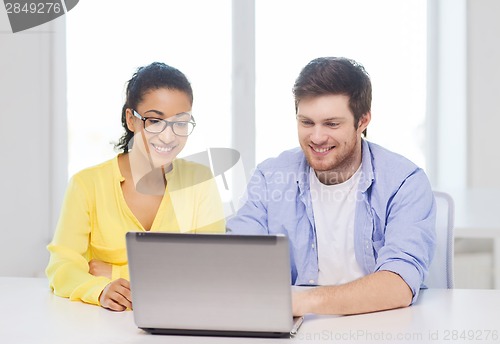 Image of two smiling people with laptop in office