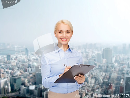 Image of smiling businesswoman with clipboard and pen