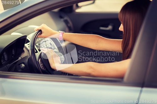 Image of woman driving a car with hand on horn button