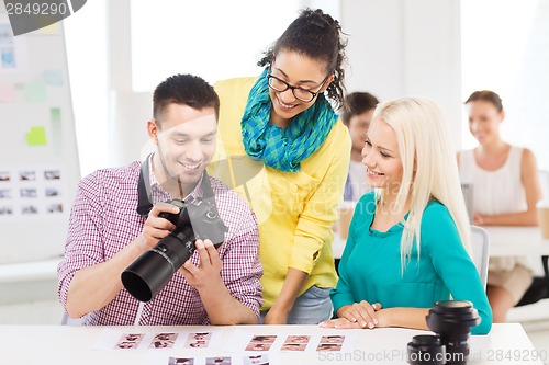 Image of smiling team with photocamera working in office