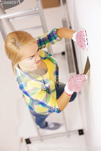 Image of smiling woman in gloves doing renovations at home