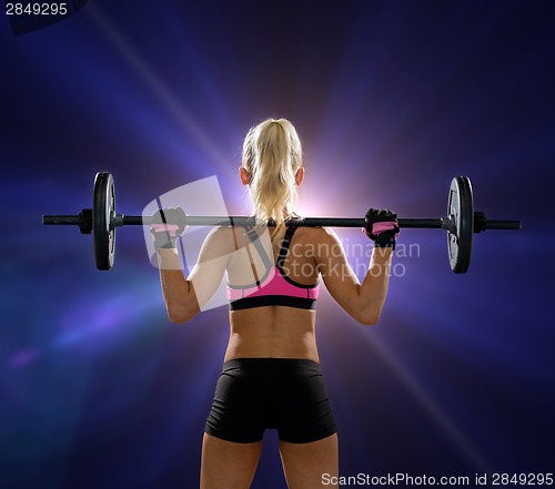 Image of sporty woman exercising with barbell from back