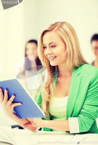 Image of smiling young girl reading book at school