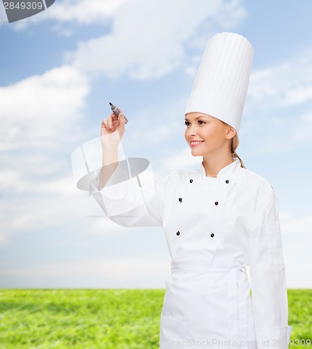 Image of smiling female chef writing something on air