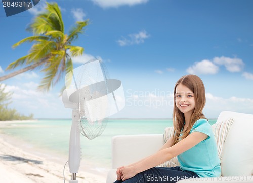 Image of smiling little girl with big fan at home