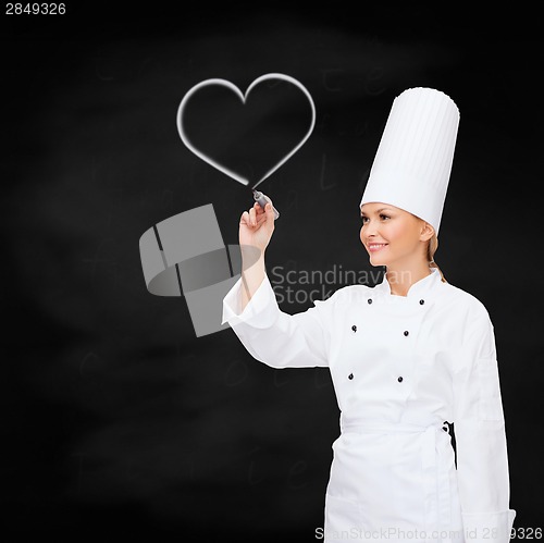 Image of smiling female chef writing something on air