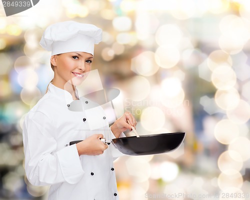 Image of smiling female chef with pan and spoon