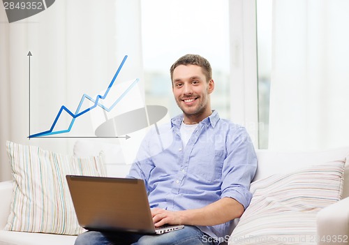 Image of smiling man working with laptop at home