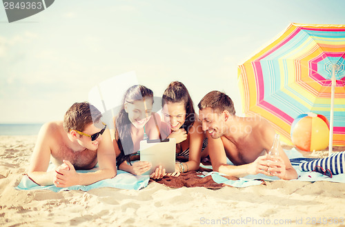 Image of group of smiling people with tablet pc on beach