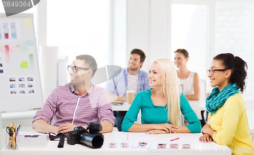 Image of smiling team with photocamera working in office