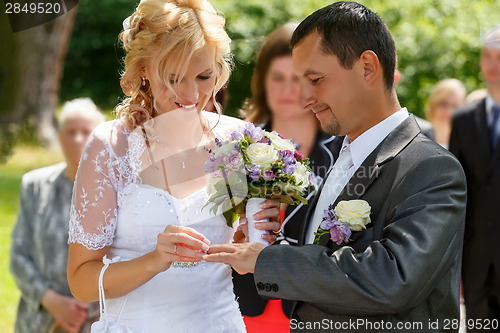 Image of beautiful young wedding couple exchange wedding rings