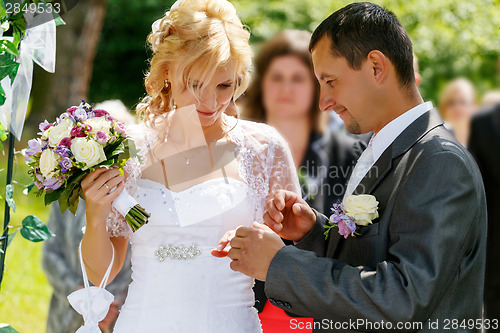 Image of beautiful young wedding couple exchange wedding rings