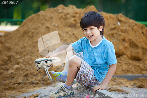 Image of boy pours the sand out of the shoe