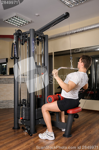 Image of Young man doing lats pull-down workout in gym