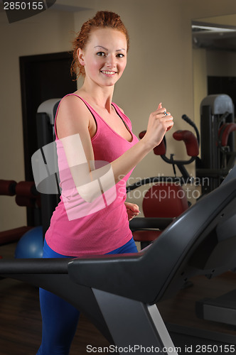 Image of young man running at treadmill in gym