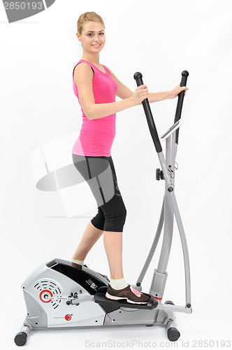 Image of young woman doing exercises on elliptical trainer