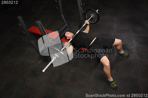 Image of young man doing bench press workout in gym