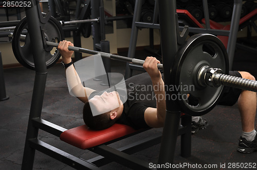 Image of young man doing bench press workout in gym