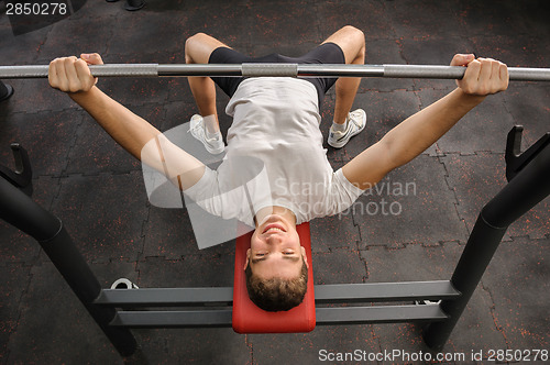 Image of young man doing bench press workout in gym
