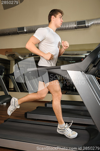 Image of young man running at treadmill in gym