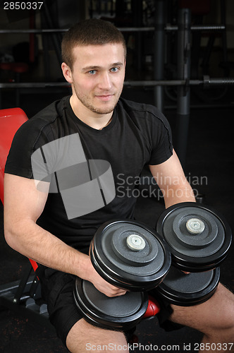 Image of young man sits after workout in gym