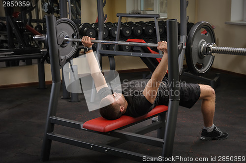 Image of young man doing bench press workout in gym