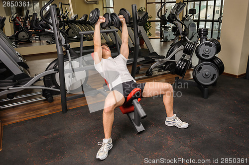 Image of Young man doing Dumbbell Incline Bench Press workout in gym