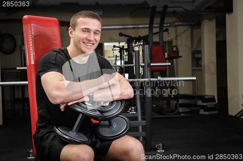 Image of young man sits after workout in gym