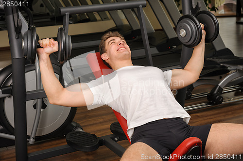 Image of Young man doing Dumbbell Incline Bench Press workout in gym