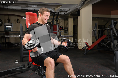 Image of Young man doing Dumbbell Biceps workout in gym