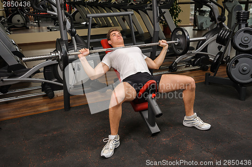 Image of Young man doing Barbell Incline Bench Press workout in gym