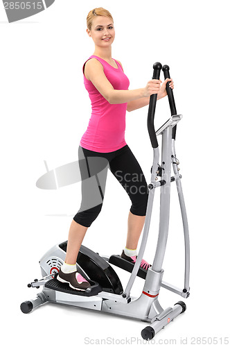 Image of young woman doing exercises on elliptical trainer