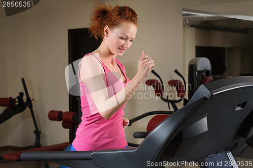 Image of young man running at treadmill in gym