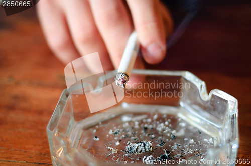 Image of hand with cigarette and ashtray