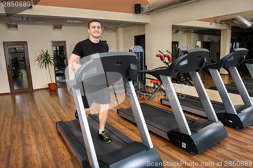 Image of young man running at treadmill in gym