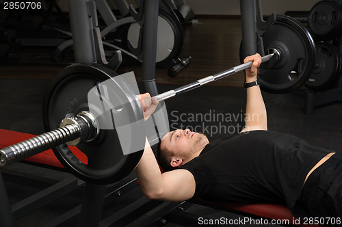 Image of young man doing bench press workout in gym