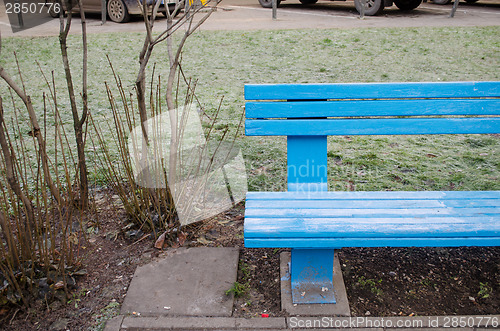 Image of blue wooden bench fragment near bush in park 