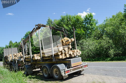 Image of heavy forest trailer with log pile along road 