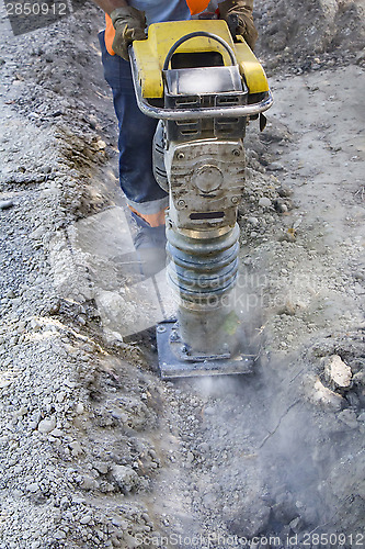 Image of Worker uses compactor