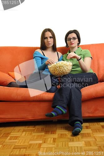 Image of female friends eating popcorn and watching tv at home