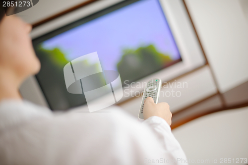 Image of young woman watching tv at home